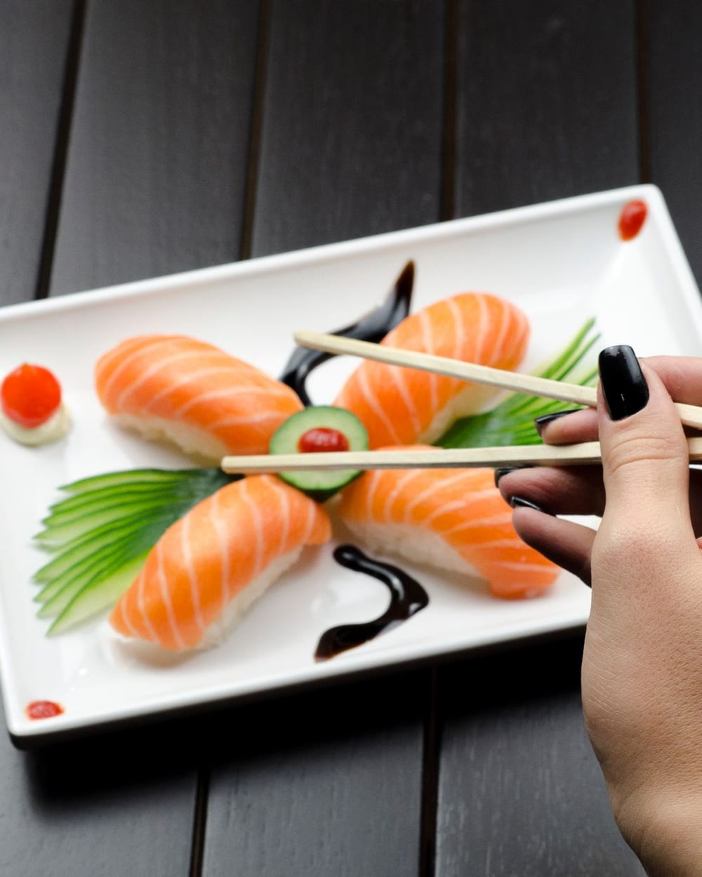 Detalhe de prato com nigiri de salmão e hashi